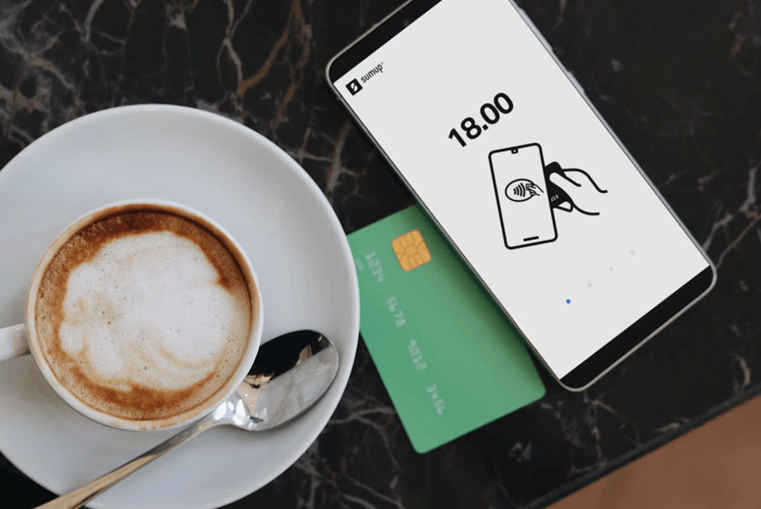 Phone payment beside coffee and cards